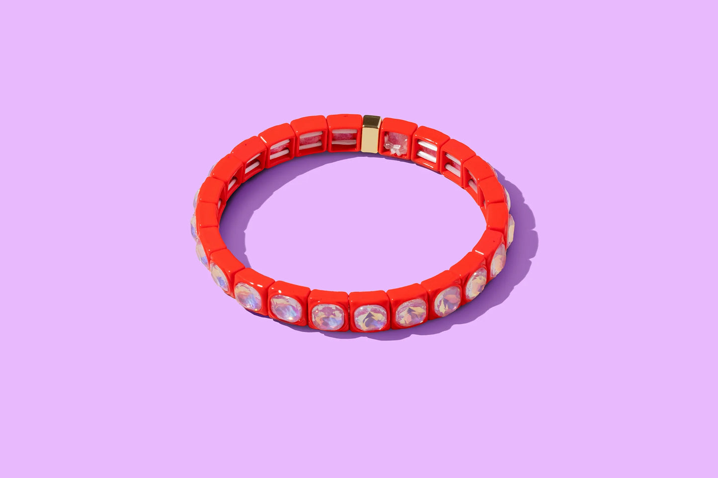 Red stretch bracelet with iridescent stones on a purple background, women's jewelry accessory