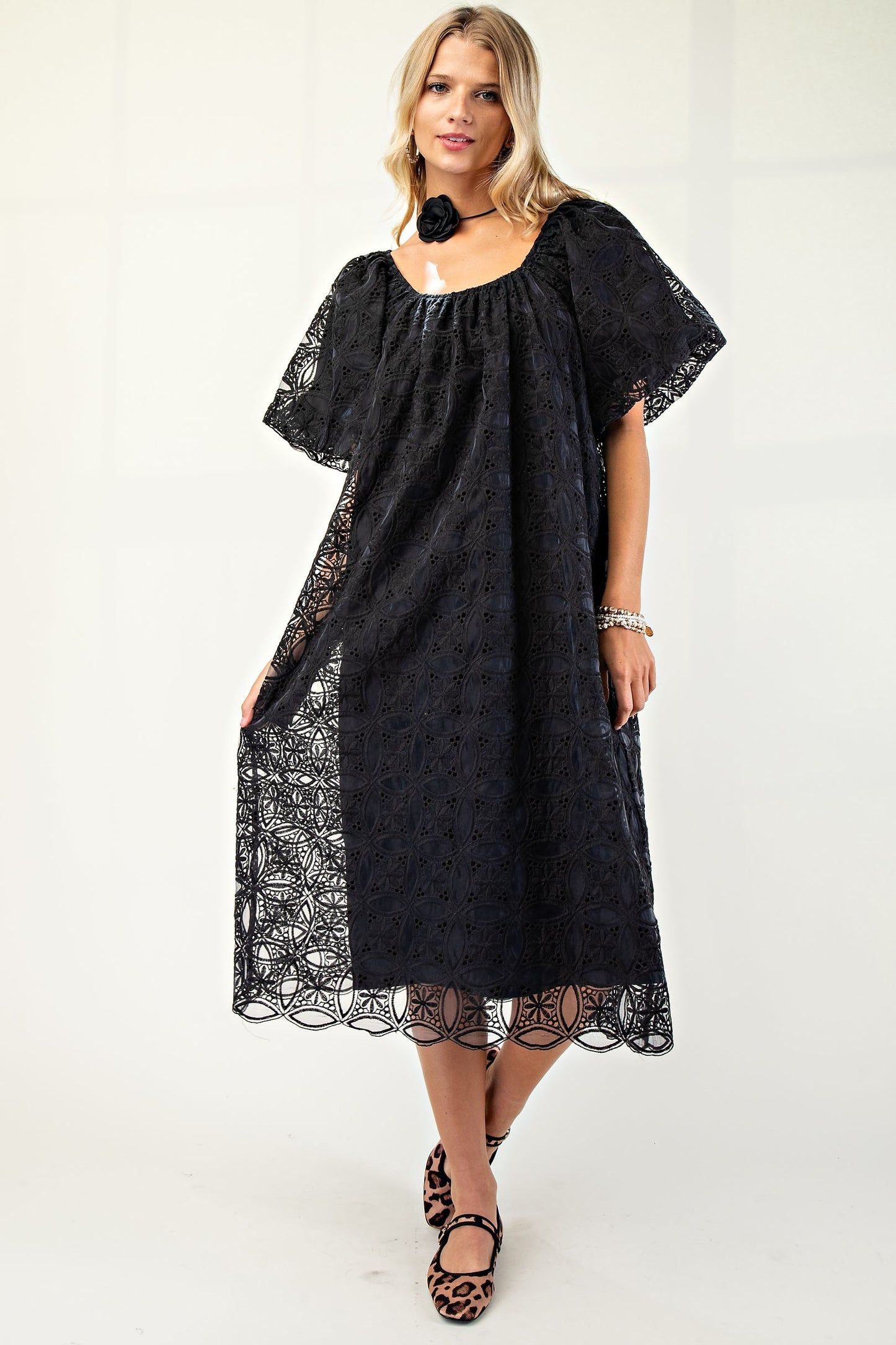 Woman wearing a black lace midi dress with flutter sleeves and leopard print shoes.