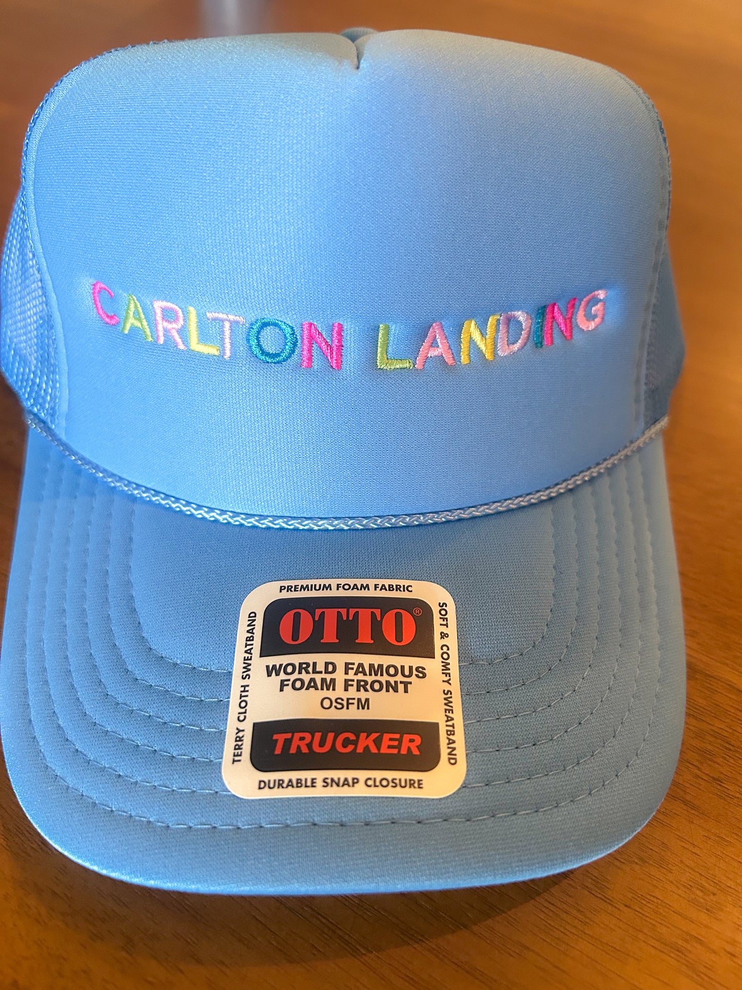 Blue cap with 'Carlton Landing' text on a wooden surface