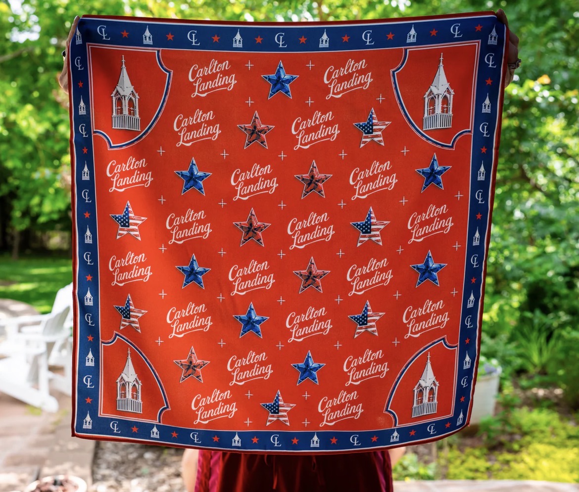 Red Scarf with 'Carlton Landing' pattern held by a person outdoors