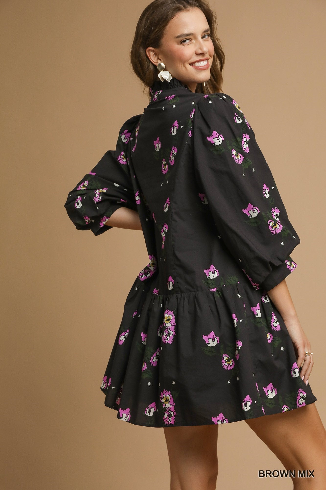 Back view of a tiered mini dress with puff sleeves and allover pink floral pattern, featuring a flowy silhouette and gathered waist detail.