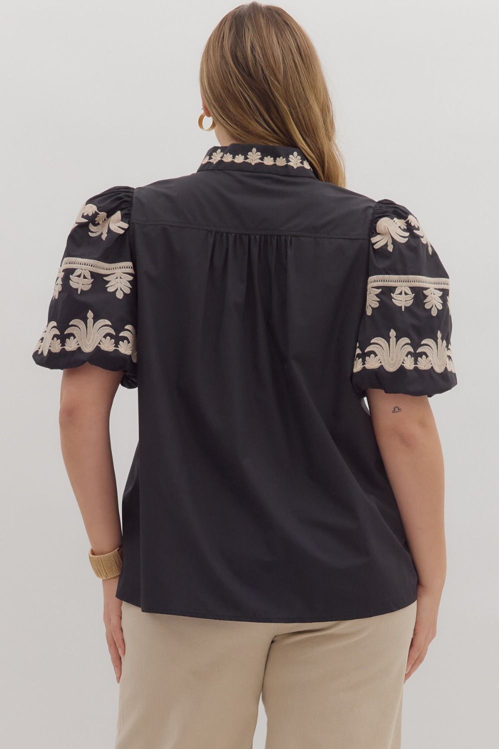 Back view of a puff-sleeve blouse showcasing embroidered detailing on the sleeves and collar with a loose, comfortable silhouette.