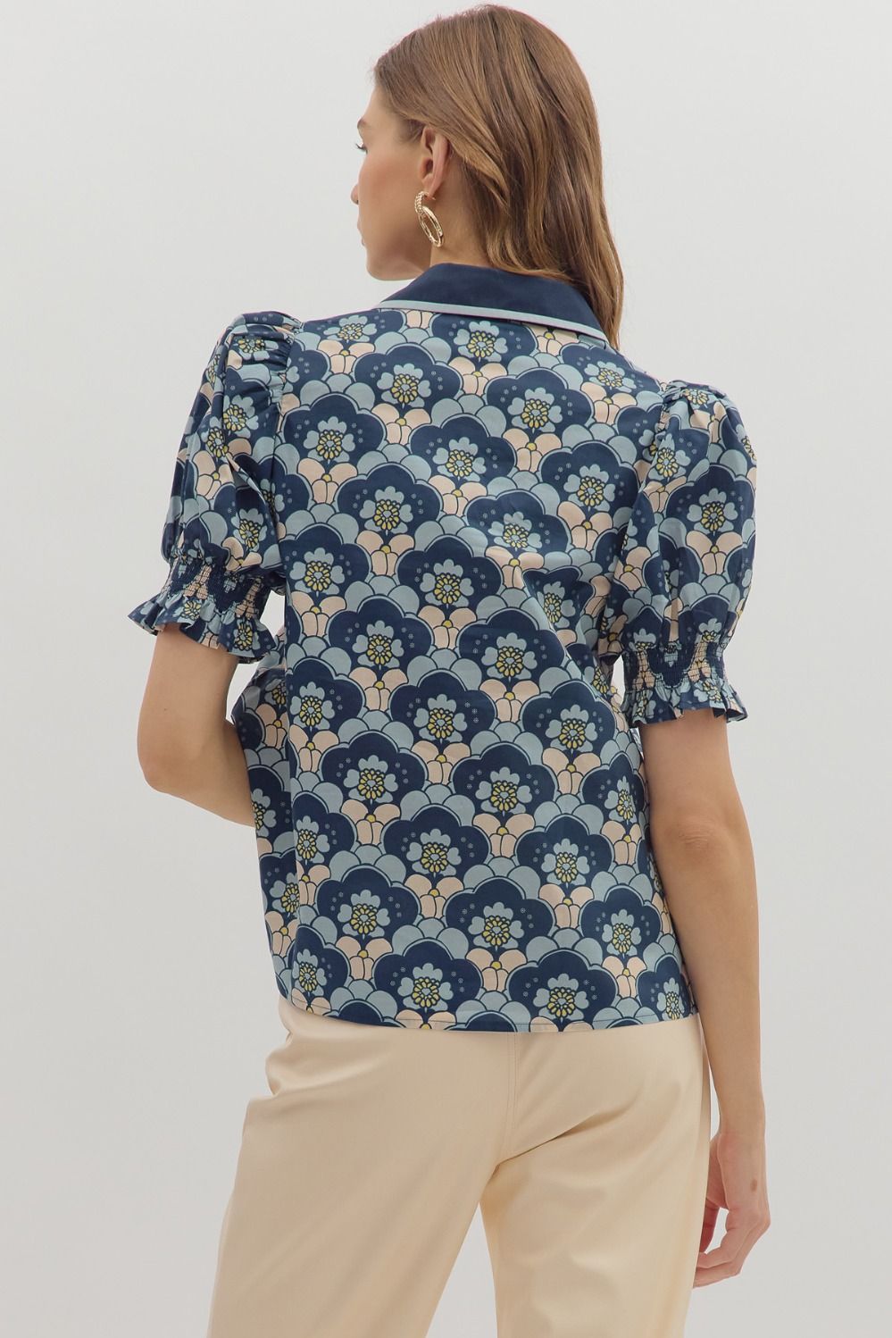 Back view of navy, blush, and sage retro floral puff sleeve blouse with smocked cuffs and contrast collar trim, paired with beige trousers – Milo & Lily Boutique.