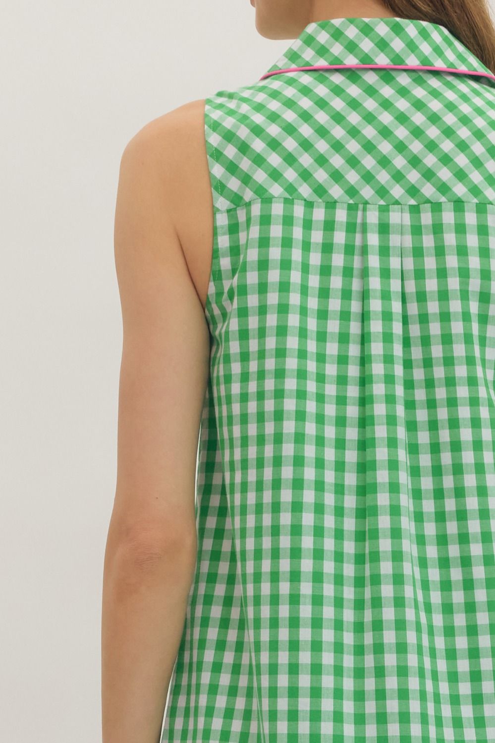 Green and white checkered sleeveless top worn by a person on a plain background
