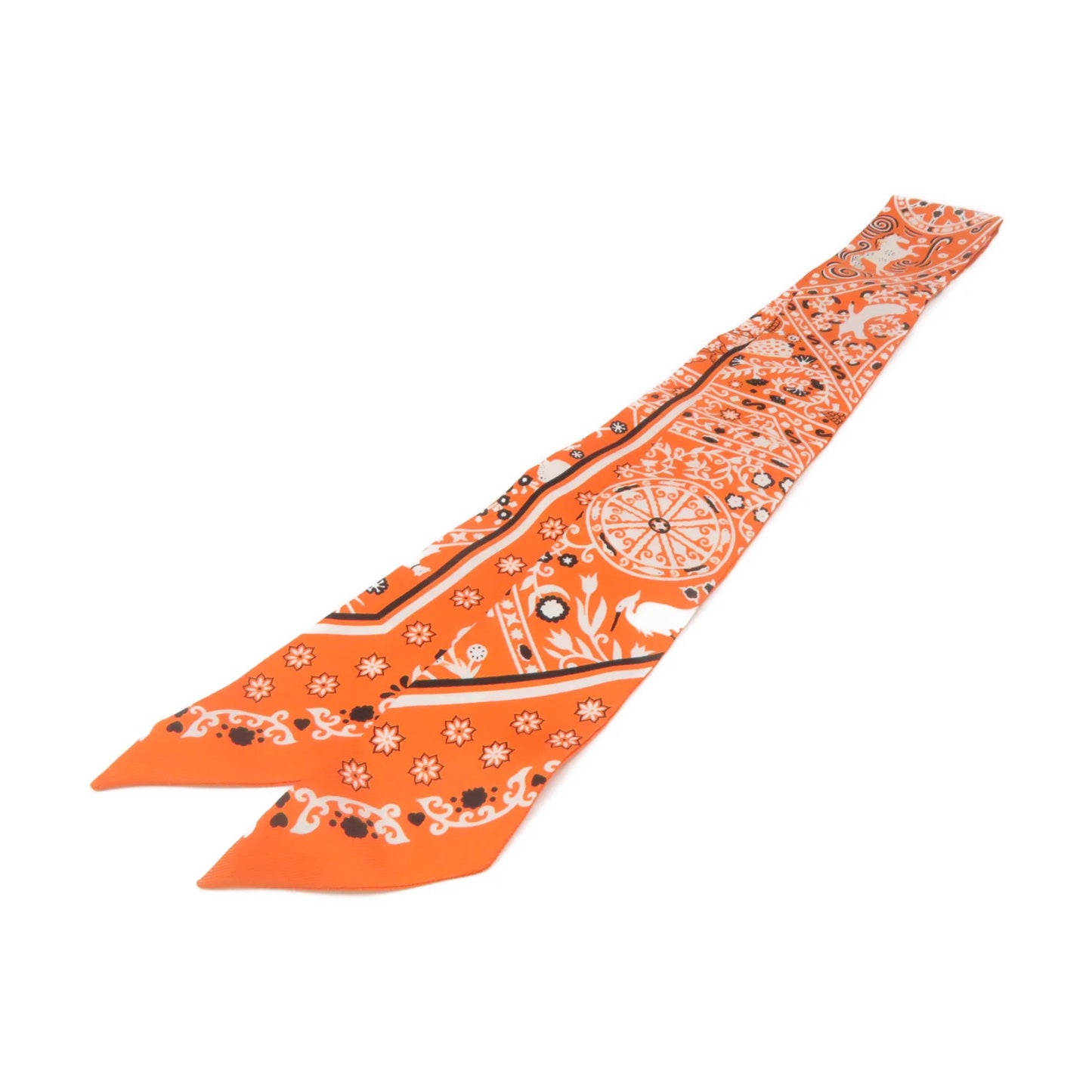 An orange silk scarf with a white and black printed pattern, laid diagonally on a plain white background.