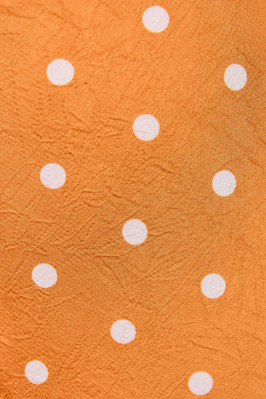 Orange textured fabric with a white polka dot pattern.