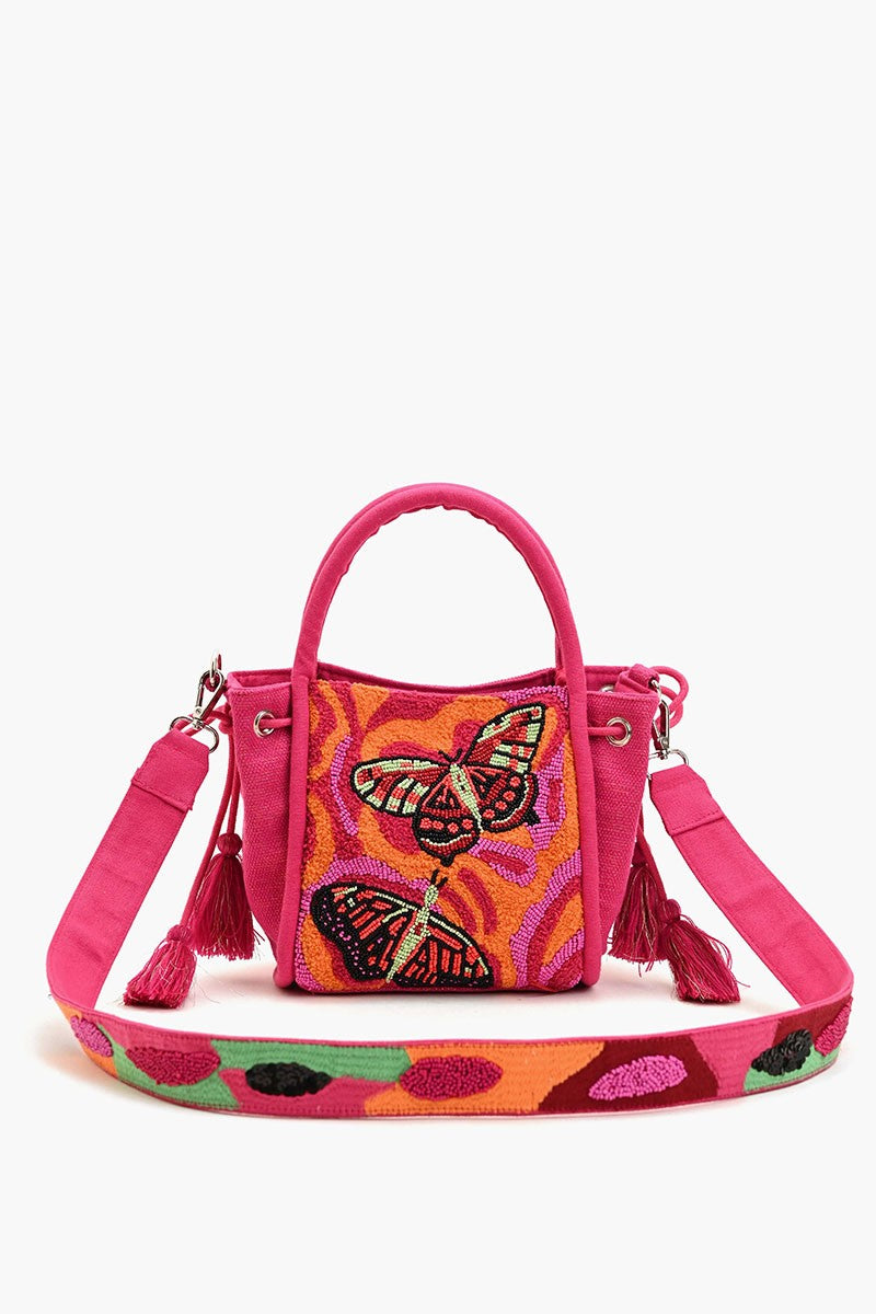 "Bright pink crossbody bag with bold hand-beaded butterfly design, colorful embroidered strap, and tassel details on the sides."