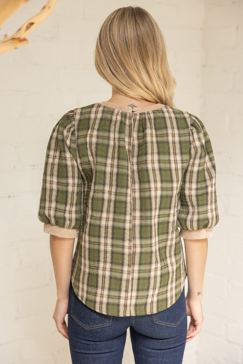 Back view of green plaid blouse with rounded hem and cuffed sleeves