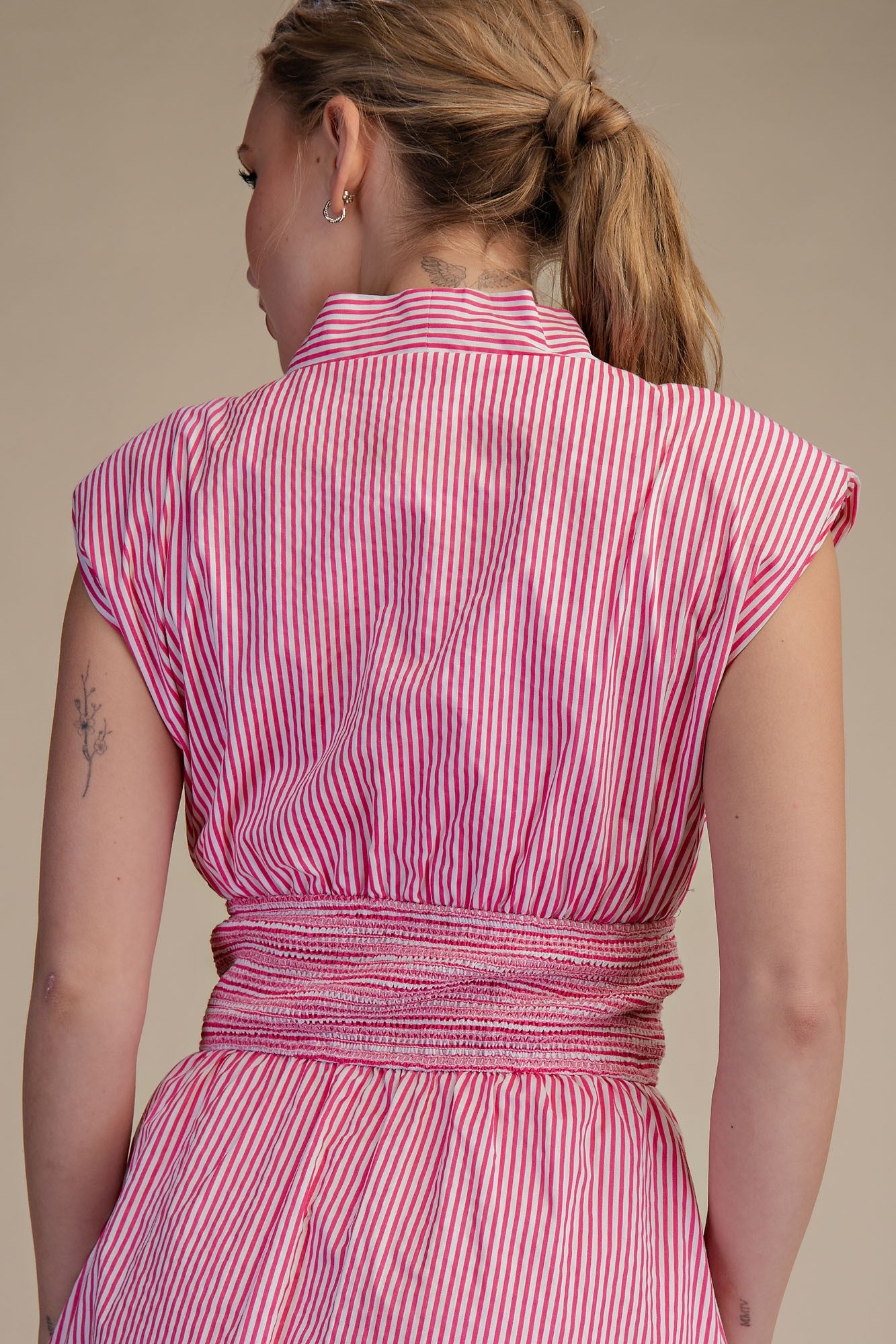 Woman wearing a pink and white striped dress against a beige background