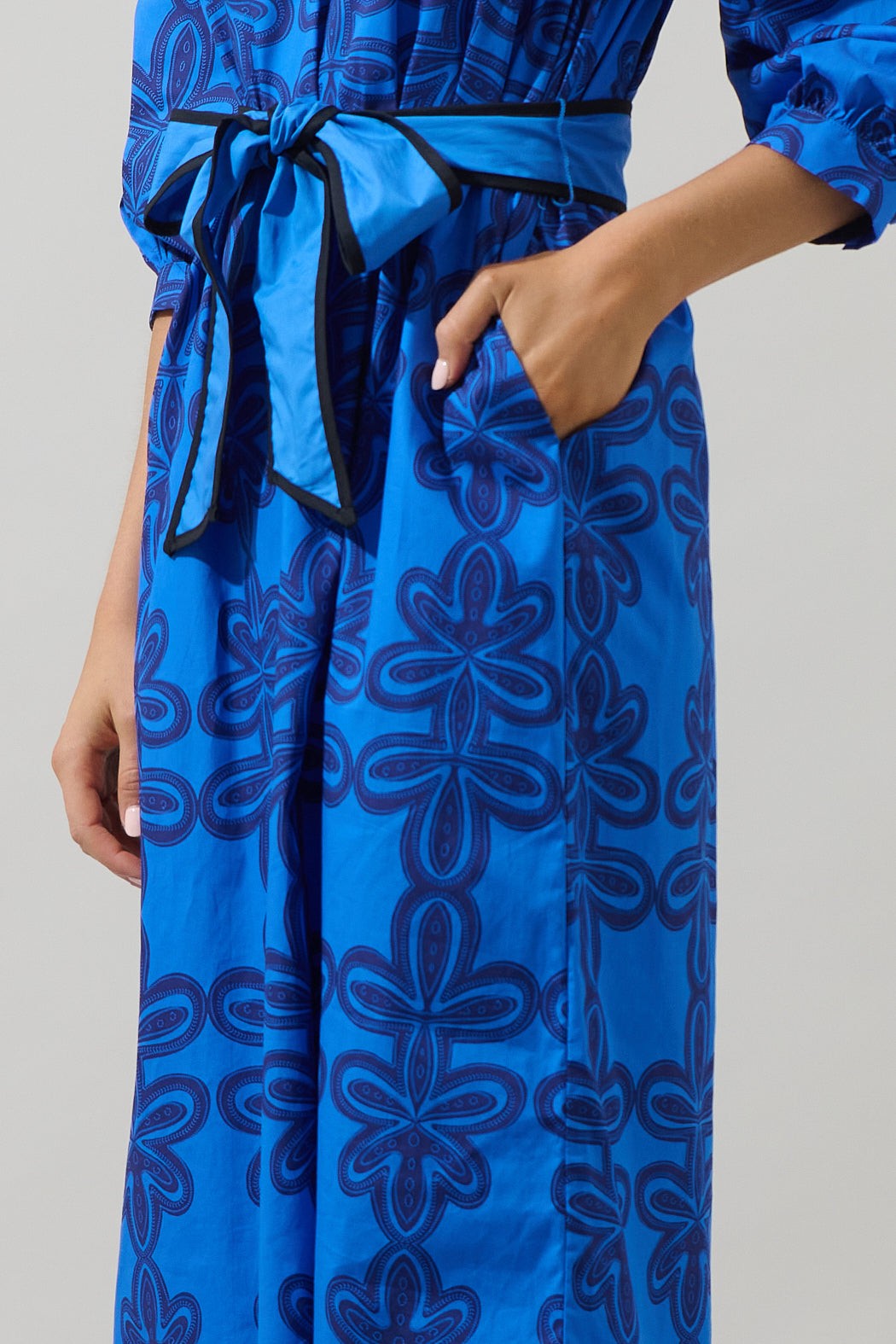 Close-up of The Autumn Sky Midi dress belt and floral pattern, highlighting the textured blue-on-blue design and flattering waist tie detail.
