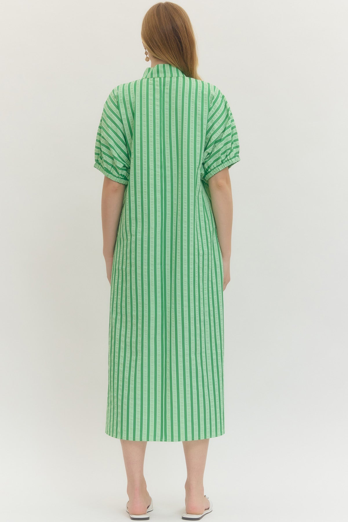 Green and white striped dress worn by a person on a white background