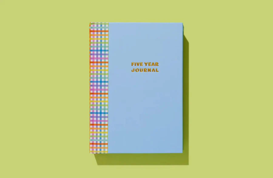 Light blue five year journal with colorful plaid spine on yellow background