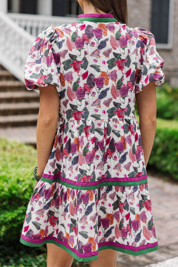 Back view of woman wearing short puff sleeve floral dress with pink and green trim outdoors