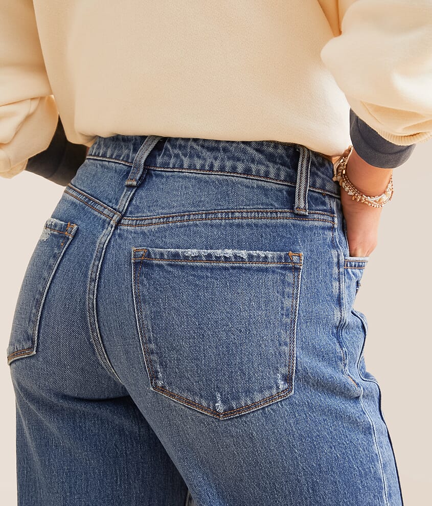 Back view of a woman wearing high-waisted blue denim jeans and a cream sweater