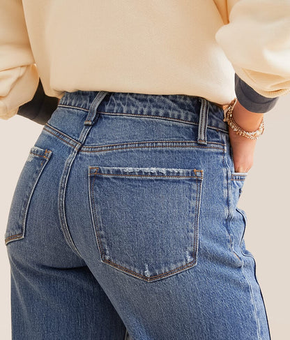 Back view of a woman wearing high-waisted blue denim jeans and a cream sweater
