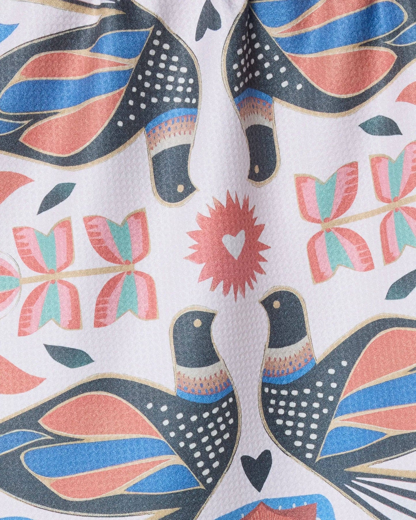 Close-up of colorful bird and floral print fabric with pink, blue, and gold details.