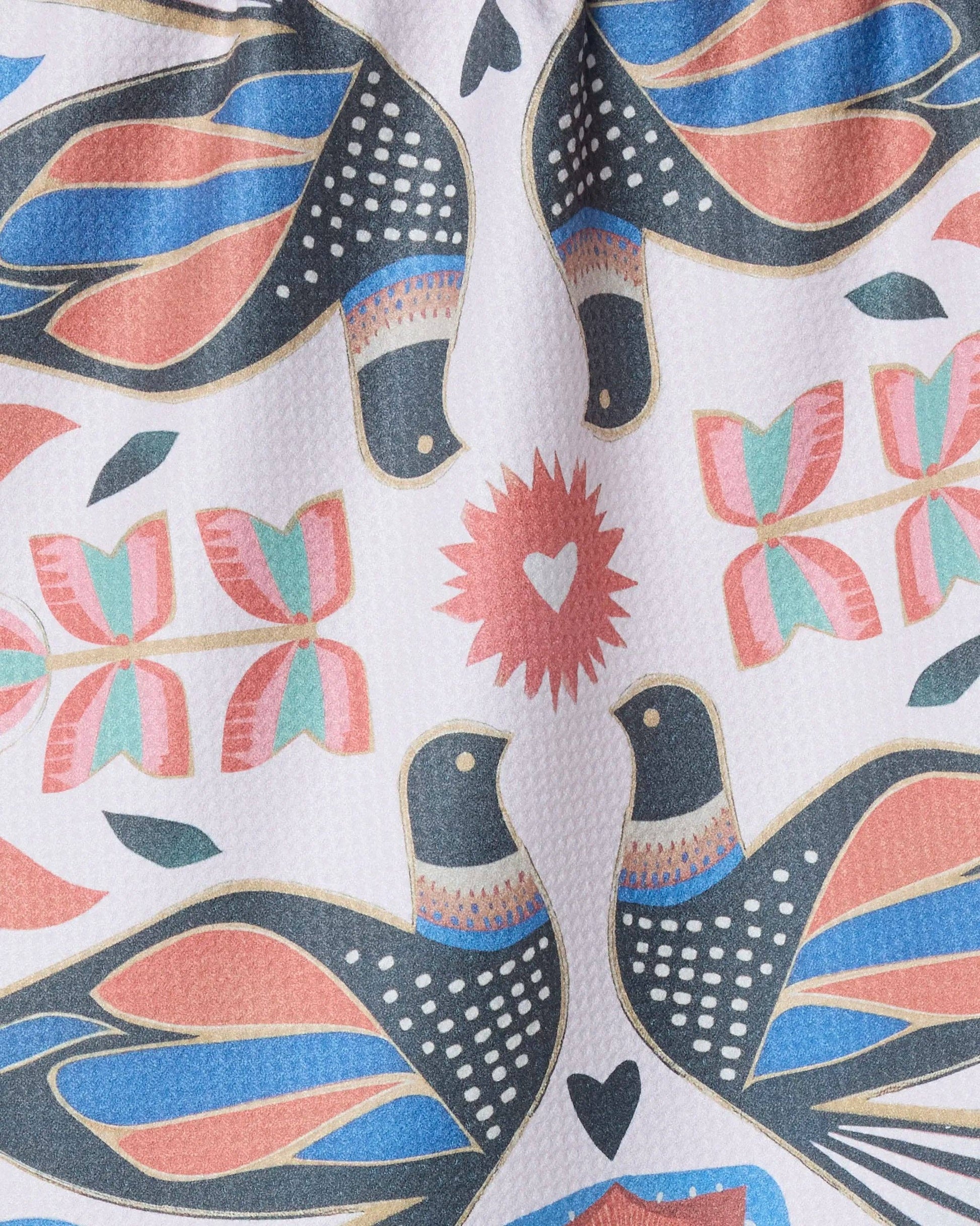Close-up of colorful bird and floral print fabric with pink, blue, and gold details.