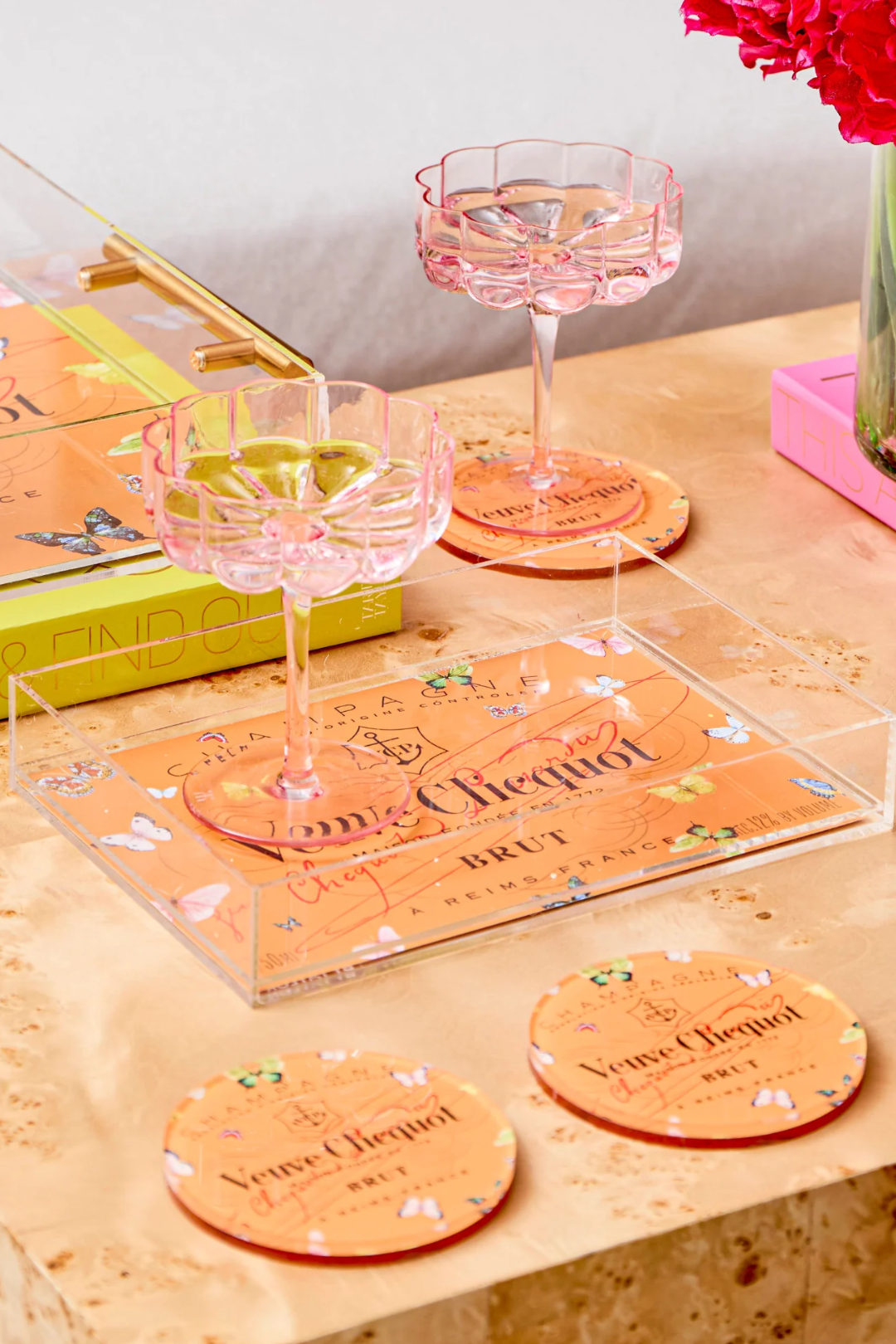 Chic tabletop decor with butterfly orange coasters, clear serving tray, and pink cocktail glasses