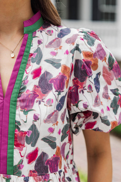 Close-up of woman wearing a puff sleeve floral blouse with pink and green trim