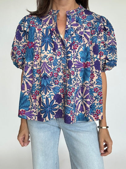 Woman wearing a puff sleeve floral blouse with blue and purple pattern and light wash jeans