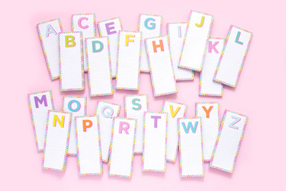 Colorful alphabet notepads with lined paper on pink background, stationery for notes