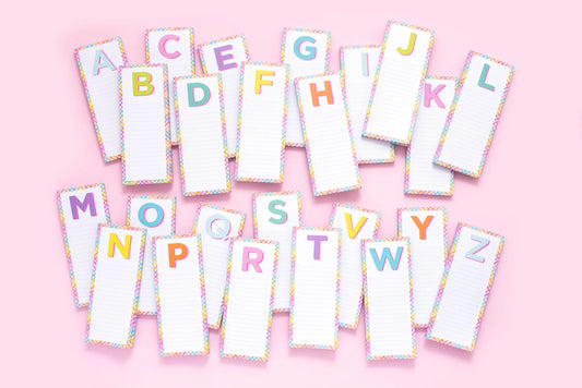 Colorful alphabet notepads with lined paper on pink background, stationery for notes