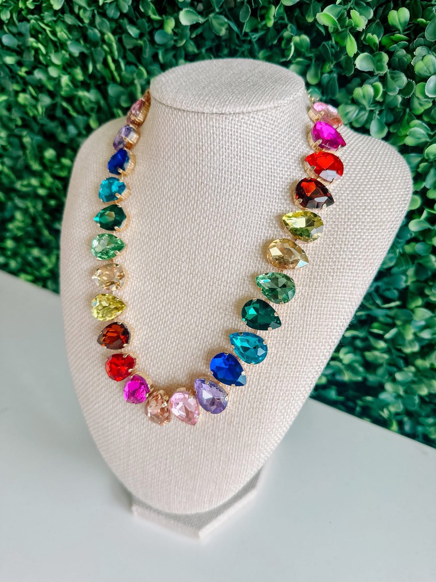Colorful gemstone statement necklace with teardrop crystals on display bust