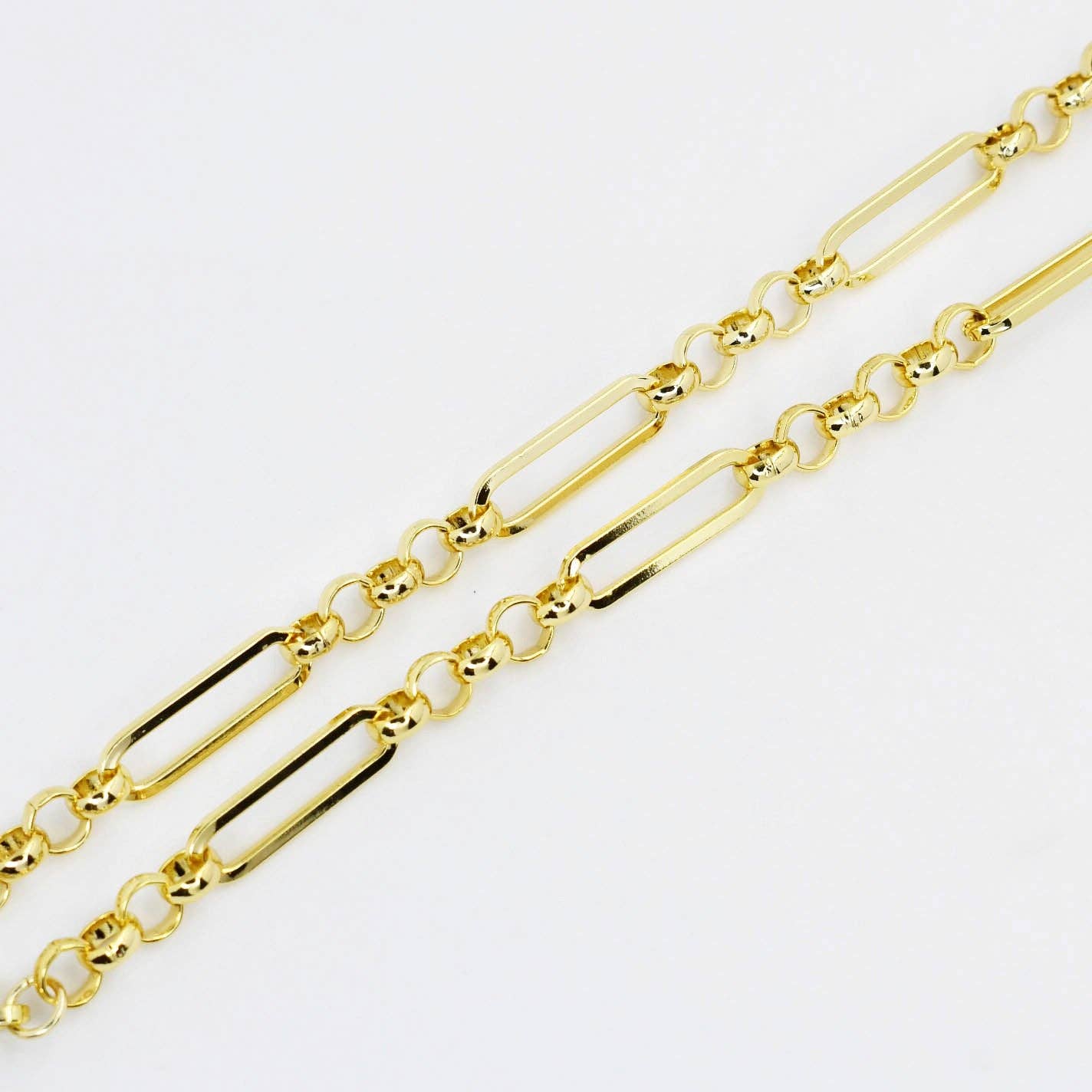 Gold chain necklace with rectangular and round links on a white background