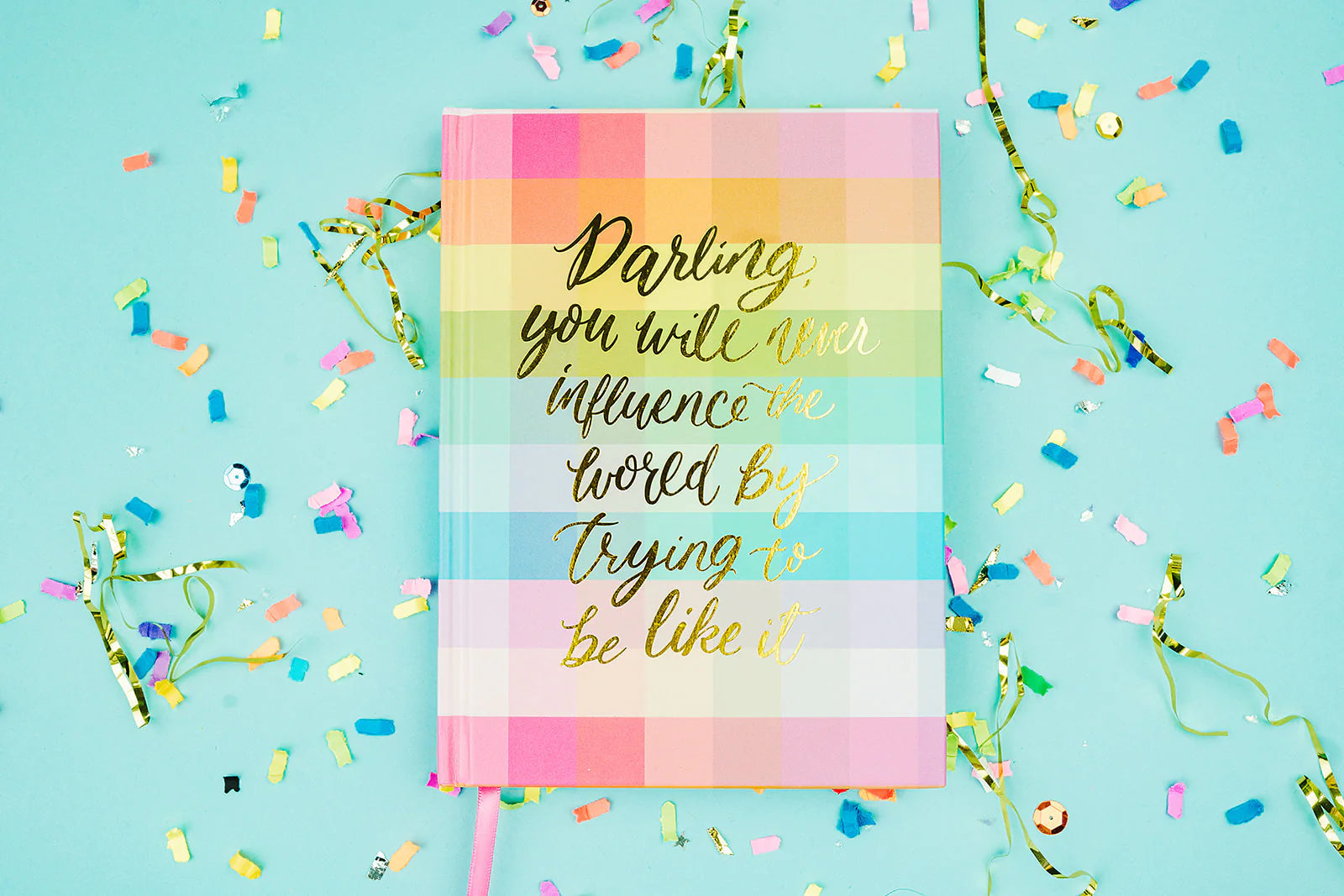 Colorful plaid journal with gold inspirational quote on blue background with confetti