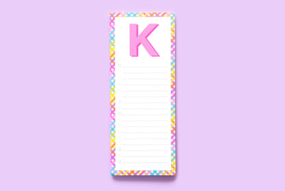 Colorful notepad with large pink letter K, rainbow border, lined checklist on lavender background
