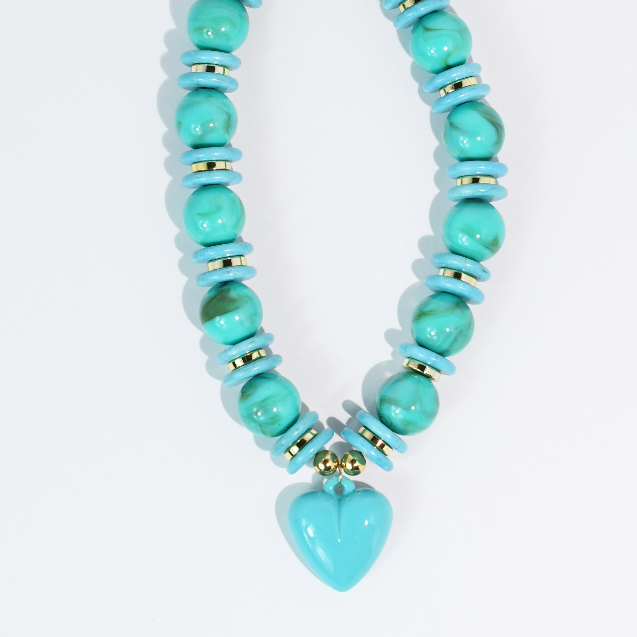 Turquoise beaded necklace with gold accents and heart pendant on white background