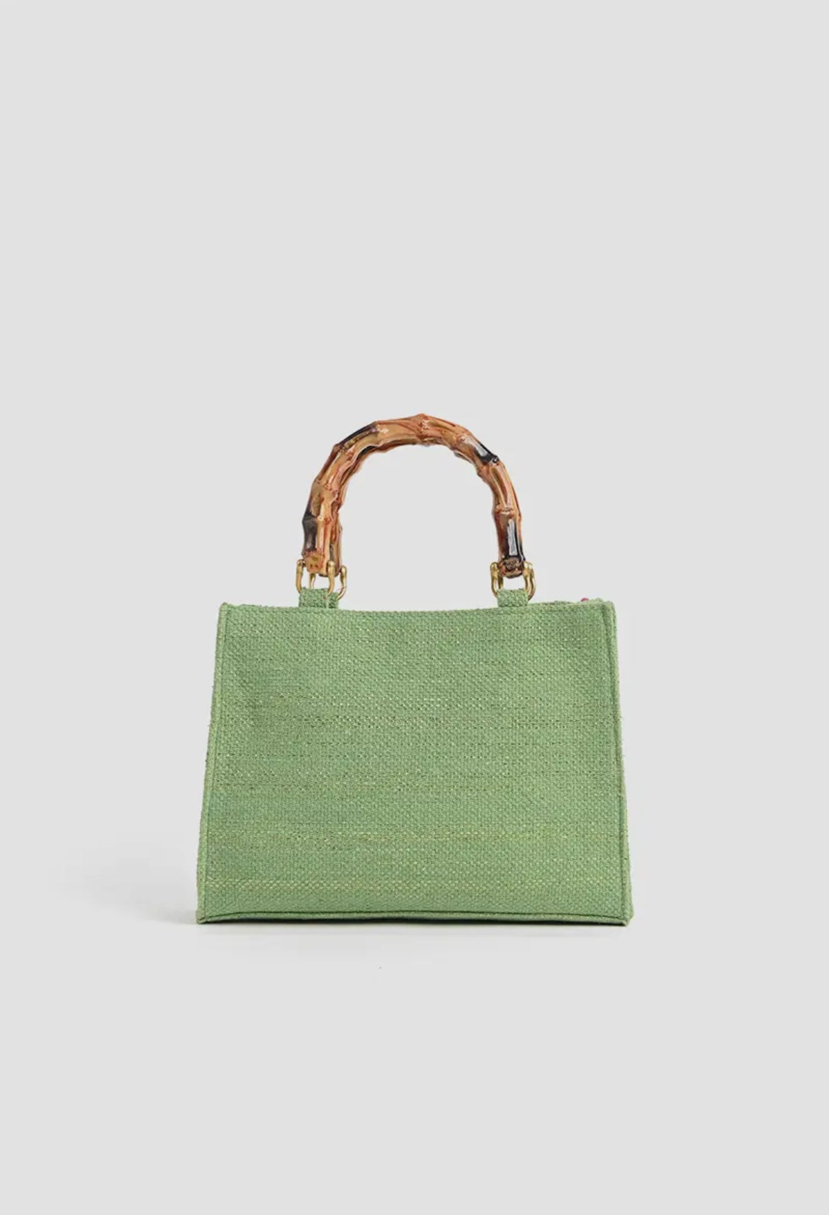 Green woven handbag with bamboo handles on white background, women's fashion accessory