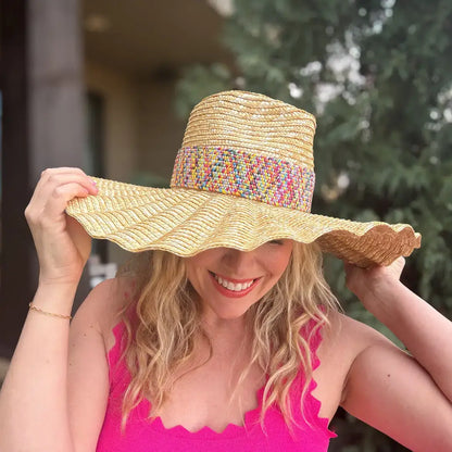 Woman in pink tank top wearing a wide-brim straw sun hat with colorful woven band outdoors