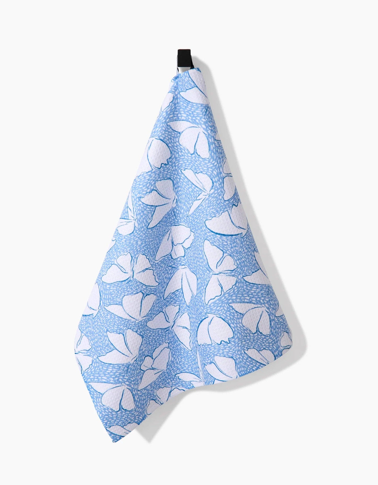 Blue and white floral patterned tea towel hanging against a white background