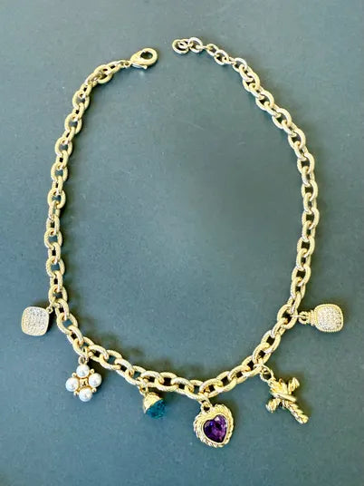 Gold chain necklace with five unique charms including a heart, cross, pearl cluster, and gemstones