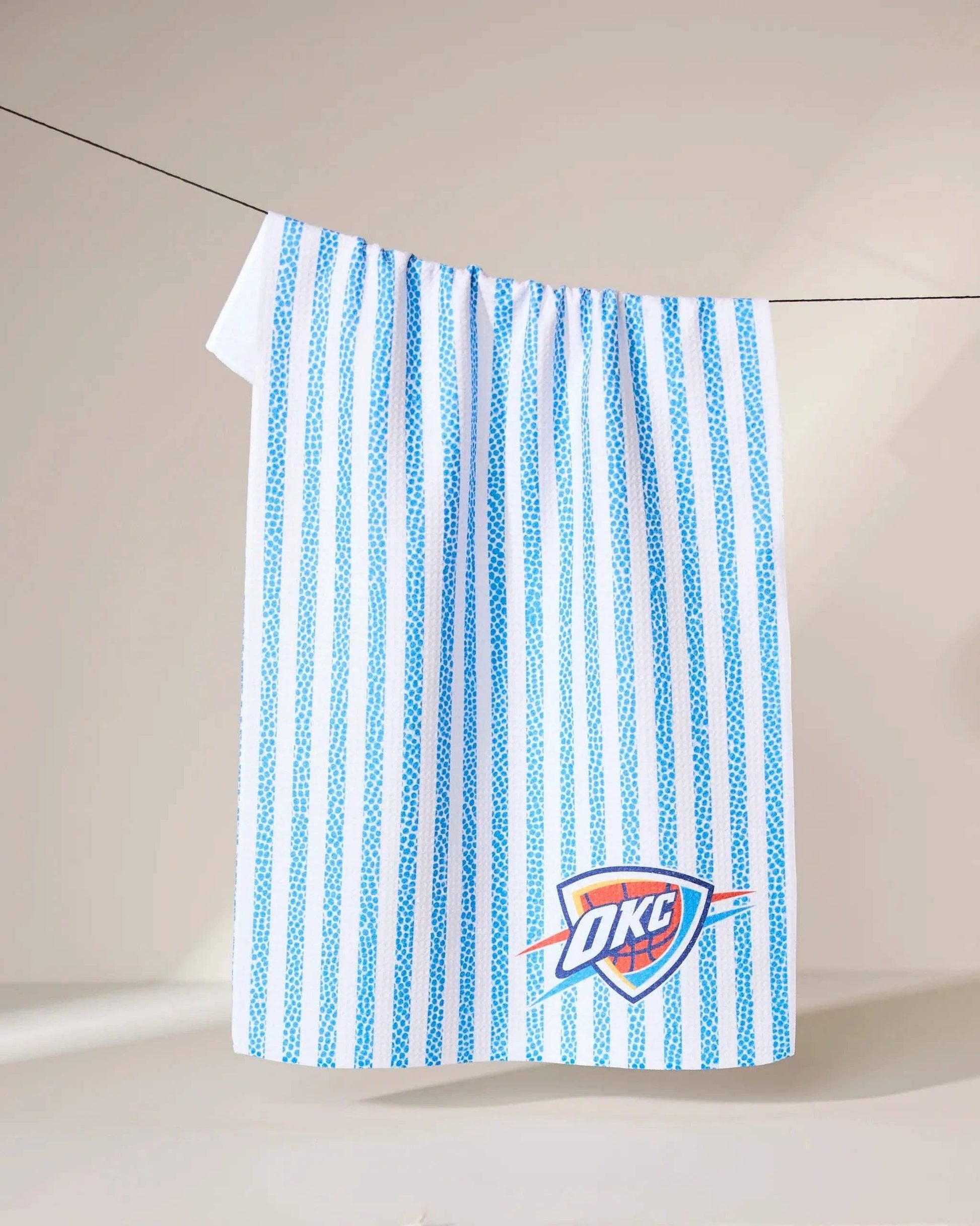 Blue and white striped towel with OKC Thunder basketball logo hanging on a line