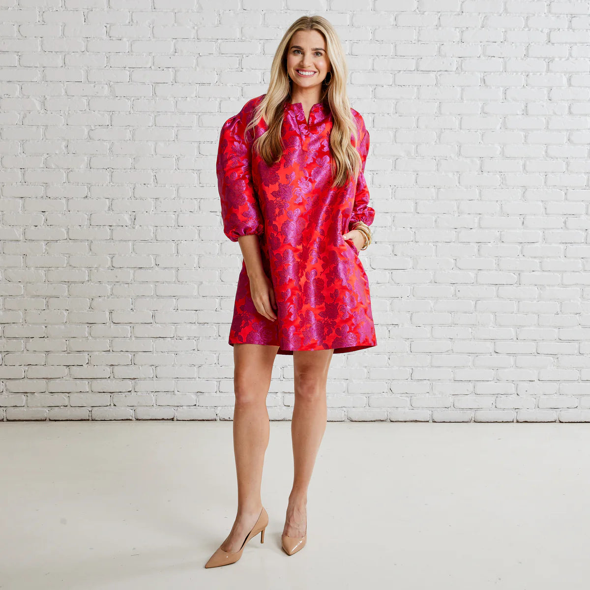 Woman wearing a vibrant floral jacquard mini dress with puff sleeves and nude heels