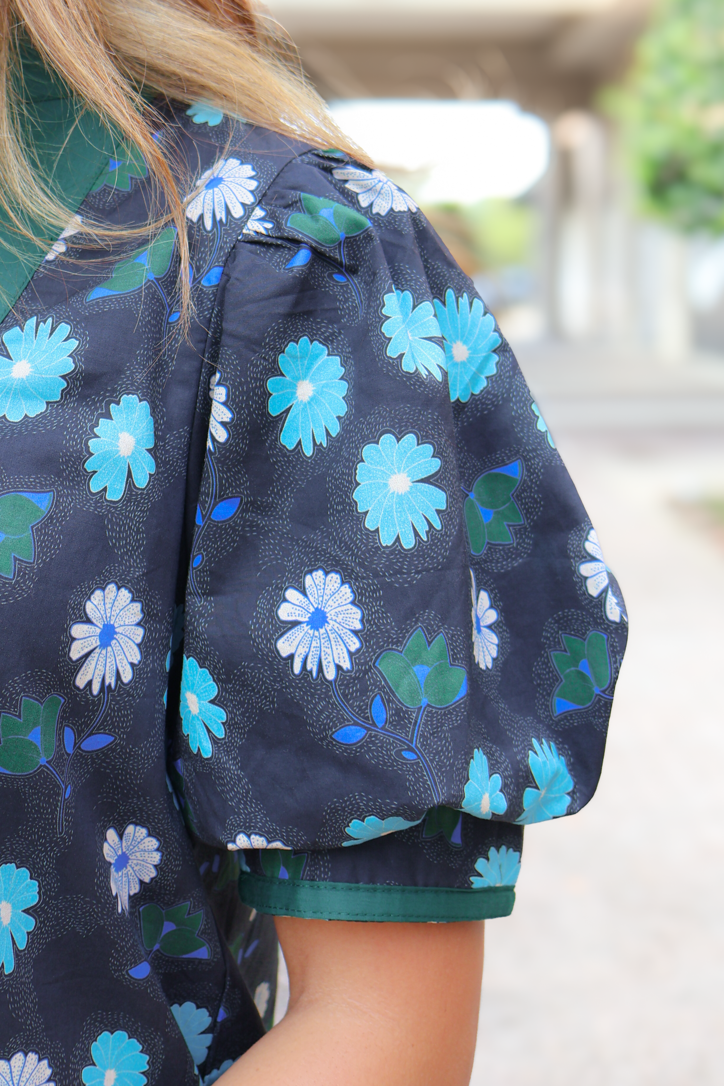 Navy blue blouse with puff sleeves and blue floral print pattern, close-up view