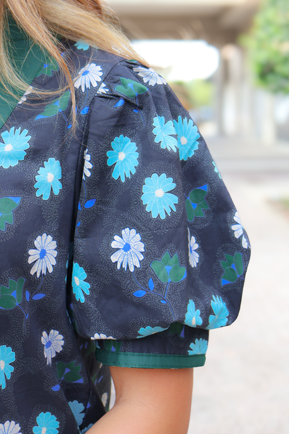 Navy blue blouse with puff sleeves and blue floral print pattern, close-up view