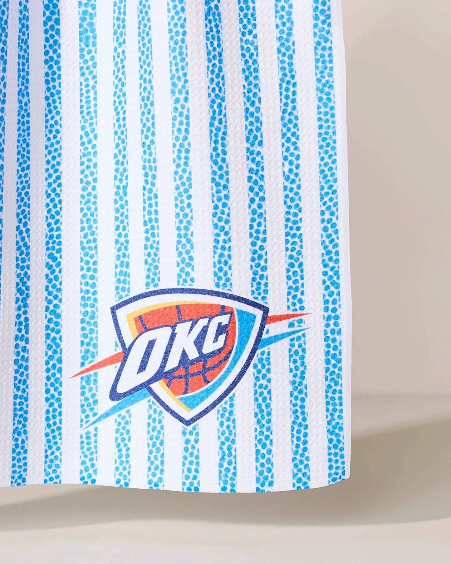 Blue and white striped fabric with OKC basketball logo, women's sports apparel detail