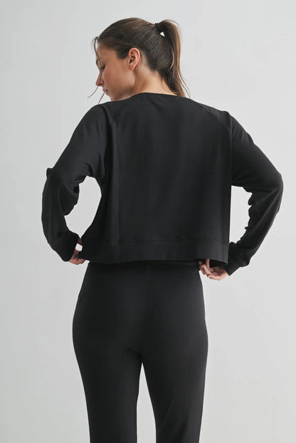 Woman wearing black long sleeve cropped top and black pants, viewed from the back