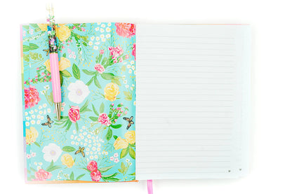 Open floral notebook with pastel flowers, gold-tip pink pen, and lined writing pages