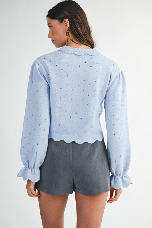 Back view of light blue scalloped knit sweater with subtle eyelet detail and ruffle cuff sleeves — boutique knitwear style.