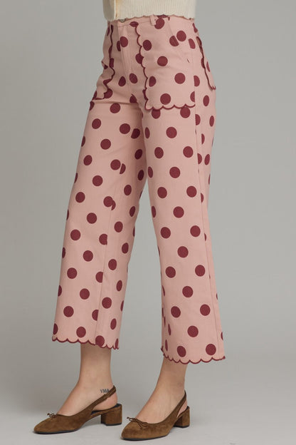 Pink pants with brown polka dots worn by a person on a gray background