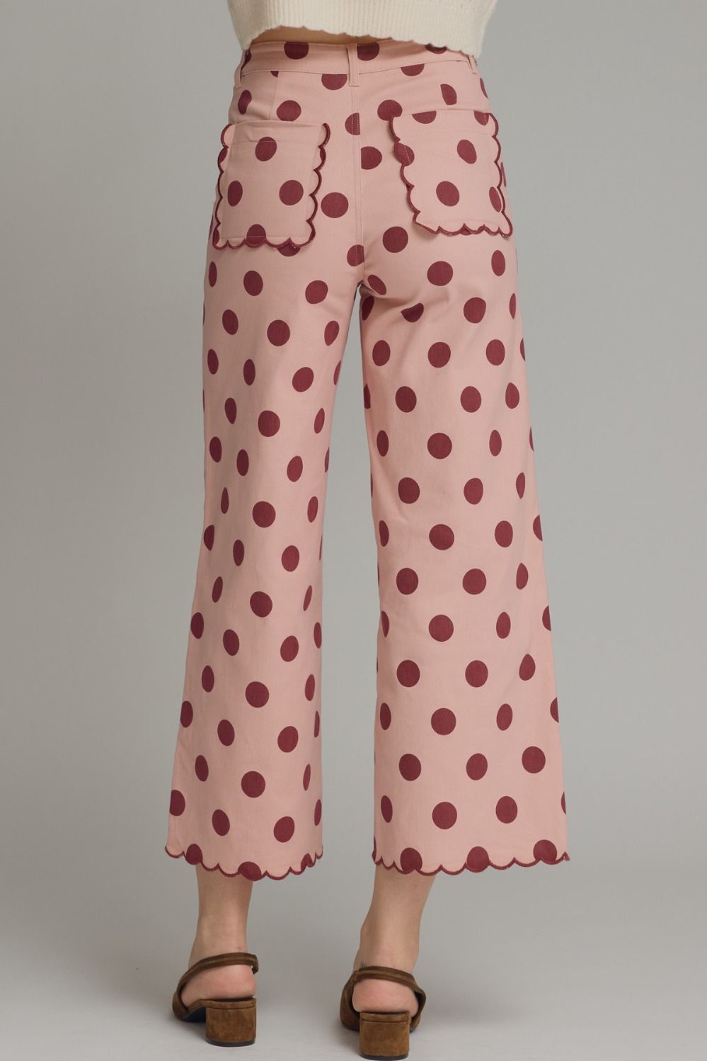 Pink polka dot pants with scalloped edges on a plain background