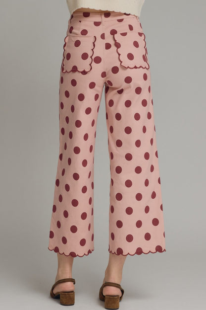 Pink polka dot pants with scalloped edges on a plain background