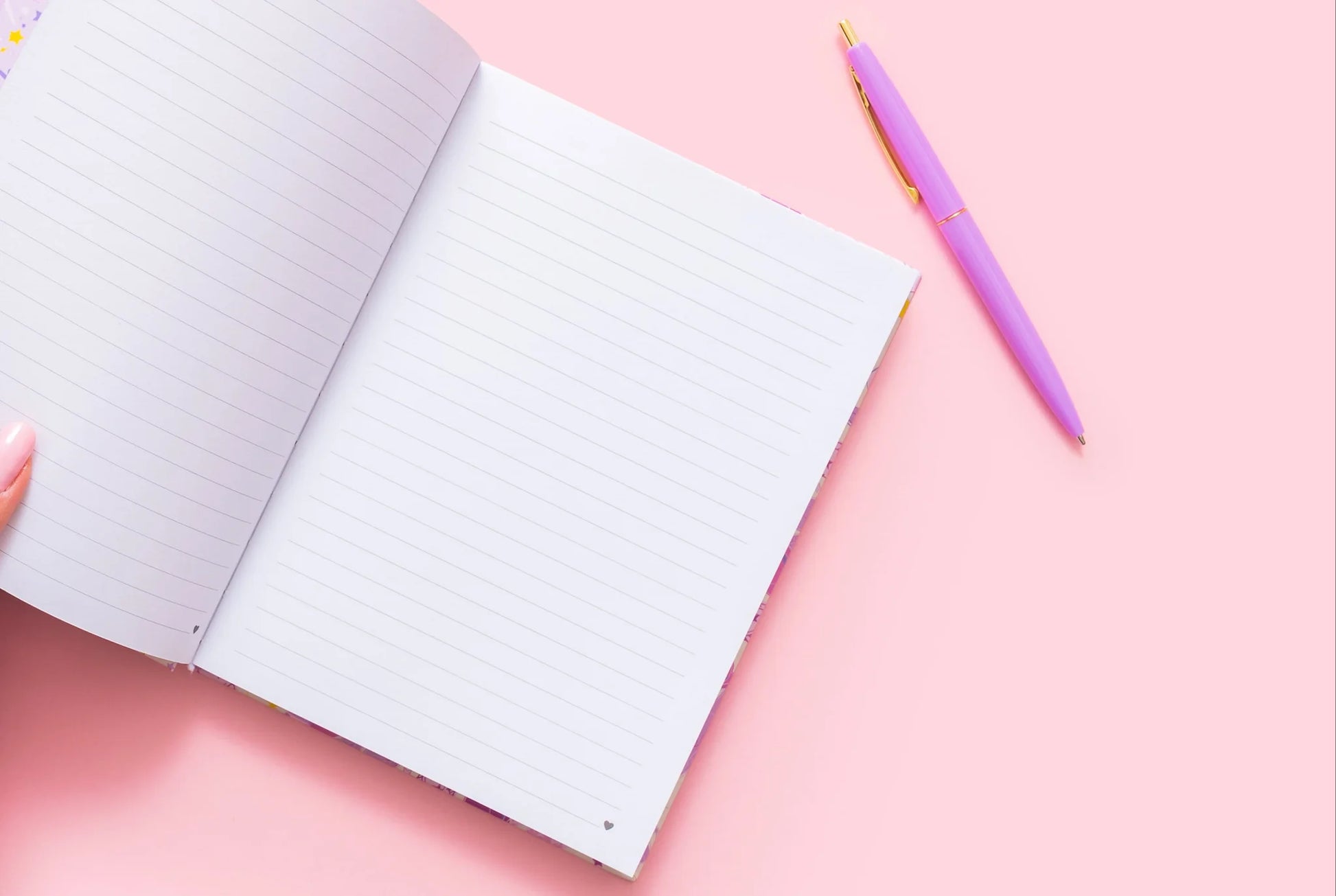 Open lined notebook and pink pen on pastel pink background, feminine stationery flat lay