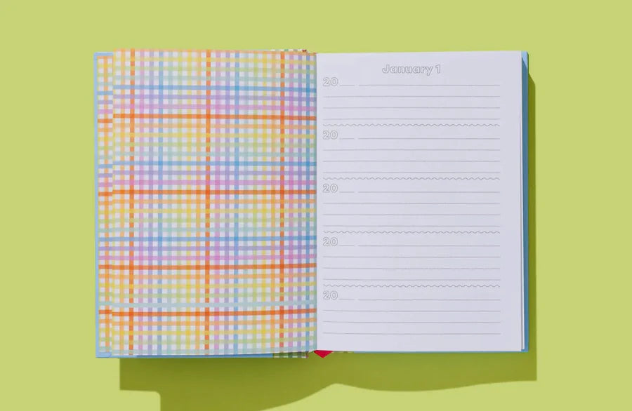 Open daily planner with colorful plaid inside cover and January 1 dated lined page