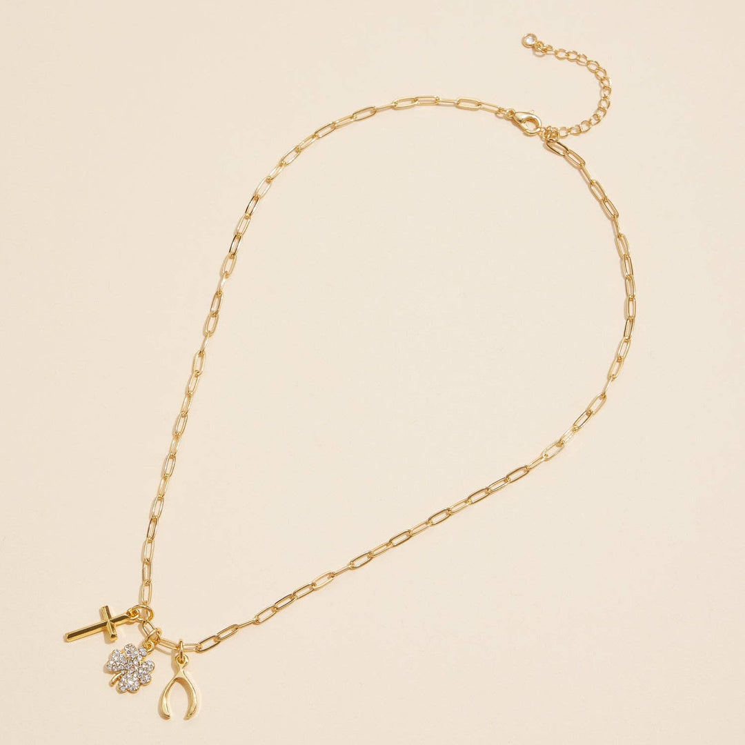 Gold chain necklace with cross, clover, and wishbone charms on neutral background