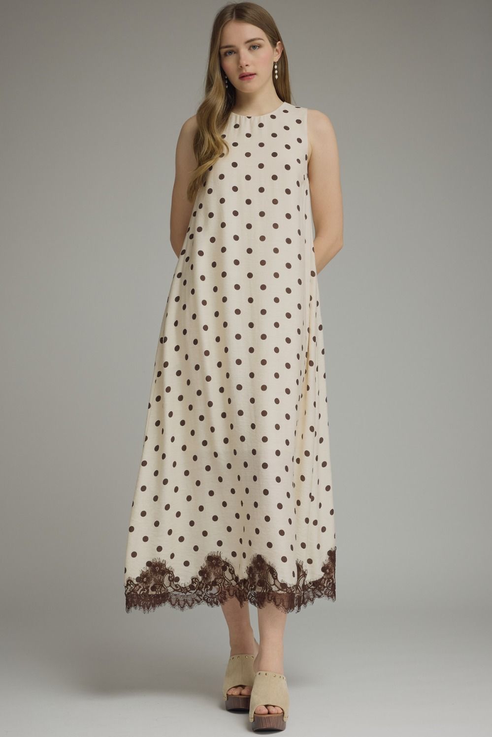 Woman wearing a polka dot dress with lace trim on a gray background